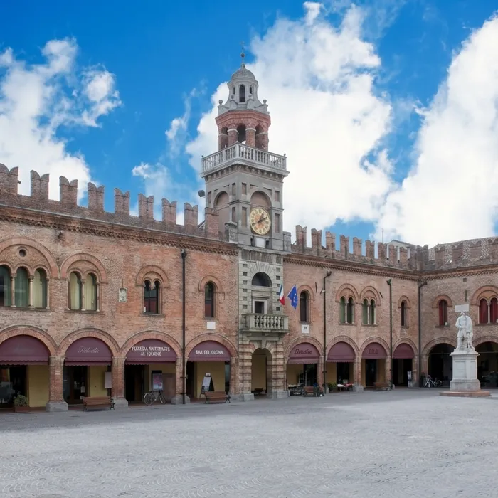 La facciata gialla e arancione della Residenza Municipale di Cento, con il portico ad archi, la balconata e il campanile a vela, con puntelli metallici sulle colonne