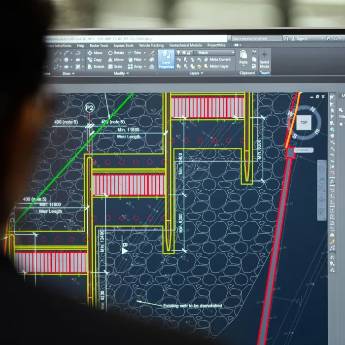 An engineer working on a structural CAD drawing across two screens
