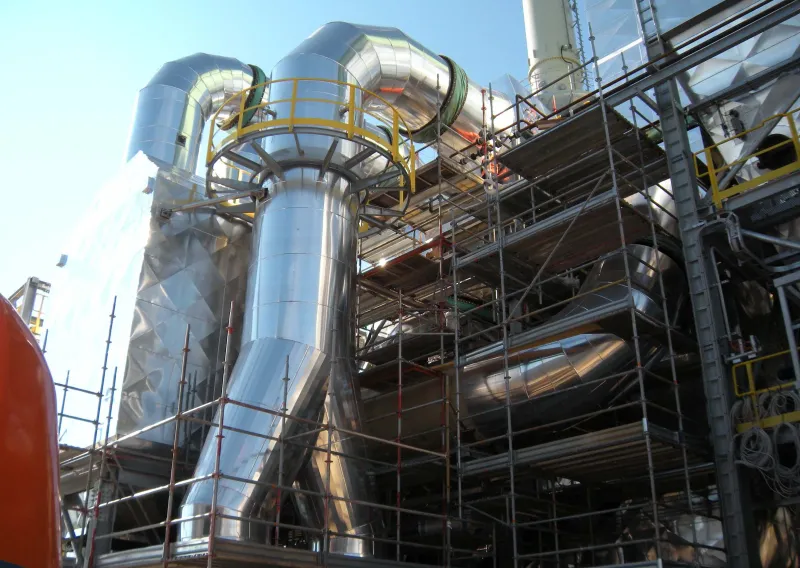 Condotte e cicloni rivestiti in acciaio della centrale a biomassa, circondati dai ponteggi di cantiere